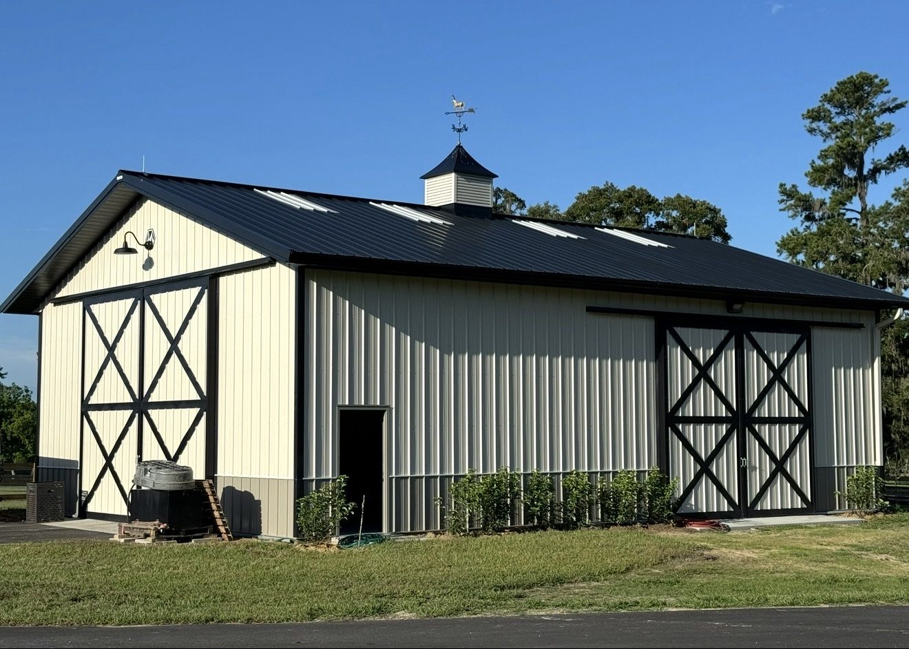 Cream-colored horse barn with a cupola and fenced paddocks on a working farm